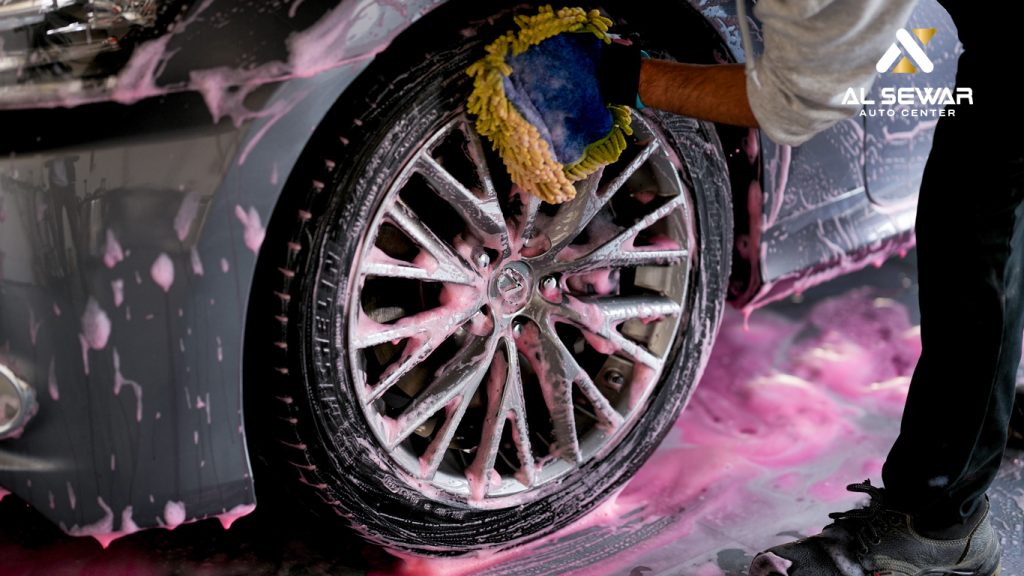 Professional car wash service in UAE – mechanic cleaning luxury car with foam and water at Al Sewar facility