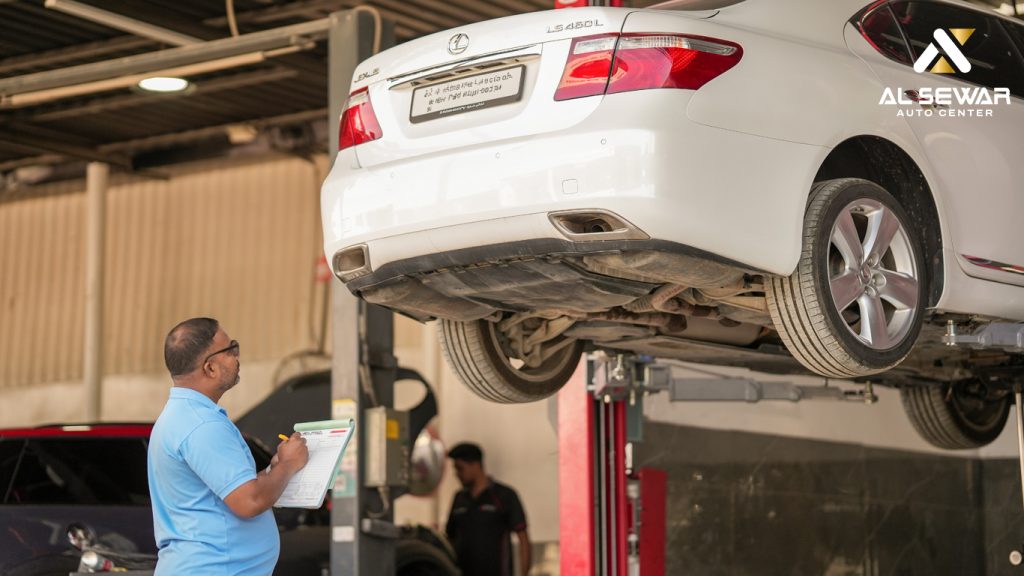 Mechanic performing routine vehicle inspection, checking under the hood of a car at a professional service center.