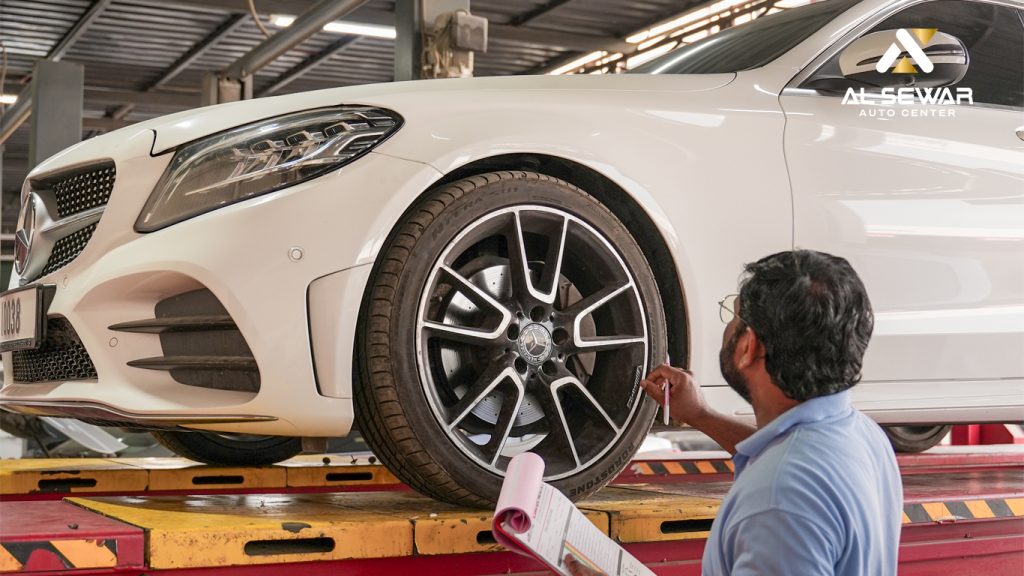 Image showing a mechanic inspecting car tires and brakes at Alsewar Auto Tyres workshop, highlighting vehicle maintenance before a road trip.