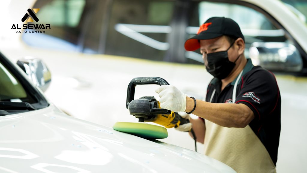 Professional auto detailing expert polishing a luxury black car’s hood using a dual-action polisher in a bright, clean workshop; vehicle surface reflecting lights after deep cleaning and correction.