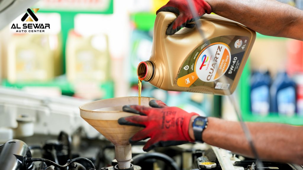 Certified technician performing professional oil change service on a vehicle at Al Sewar Auto Service Center.