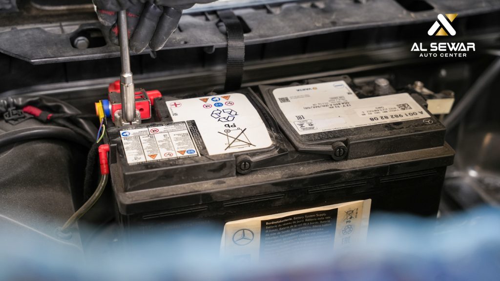 Mechanic inspecting and replacing a car battery at a professional auto service center in the UAE, showcasing battery maintenance and replacement services under Al Sewar Auto Center.