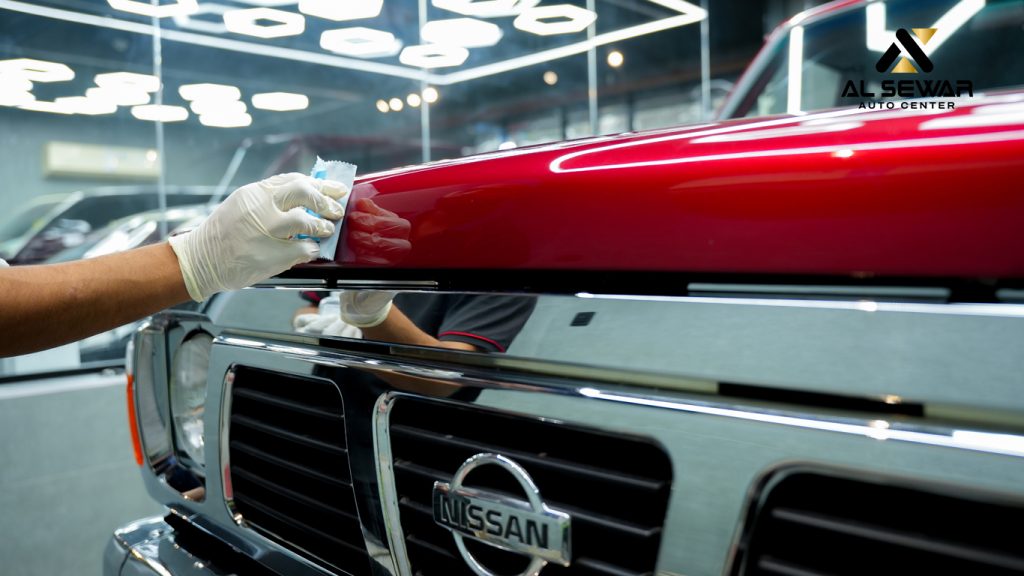 Mechanic applying high-gloss ceramic coating on a black car at Al Sewar Auto Center Fujairah, showcasing water beading and mirror-like finish.