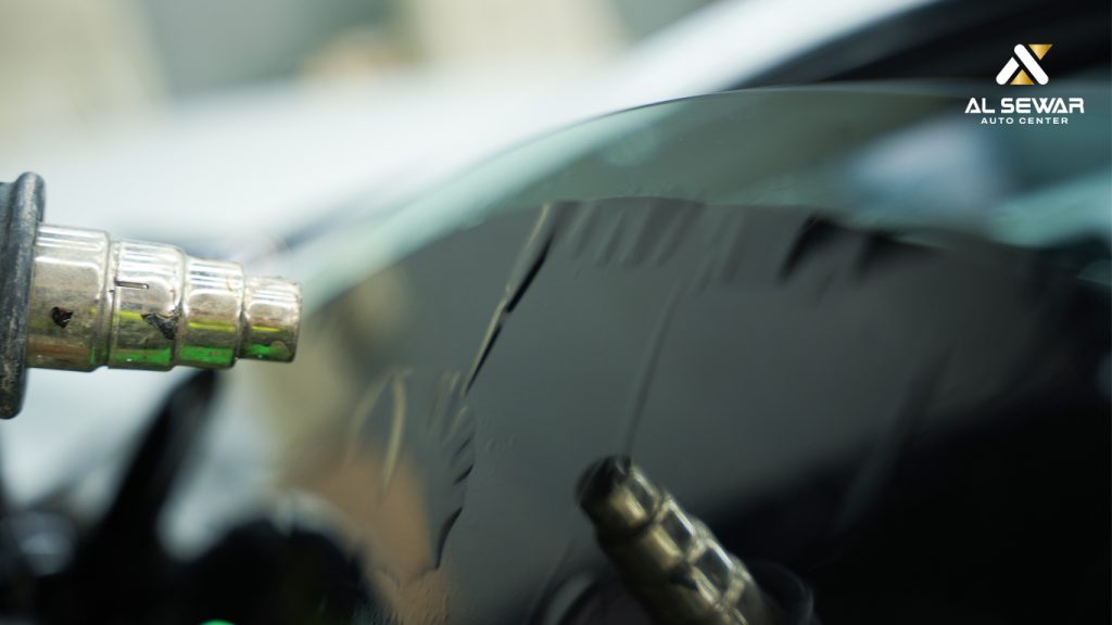 Close-up of window tint film being applied with a heat gun at Al Sewar Auto Center in Dubai