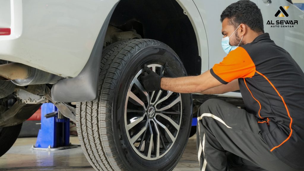 Mechanic installing a stylish alloy rim on a car at Al Sewar Auto Center.
