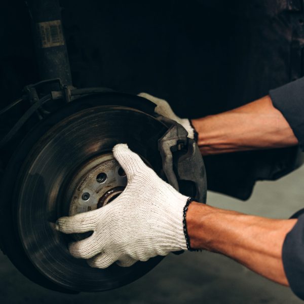 Cropped view of the man car inspection measure quantity inflated rubber tires car. Closeup hand holding tire and black car. Tyre pressure measurement for automobile. Car industry concept